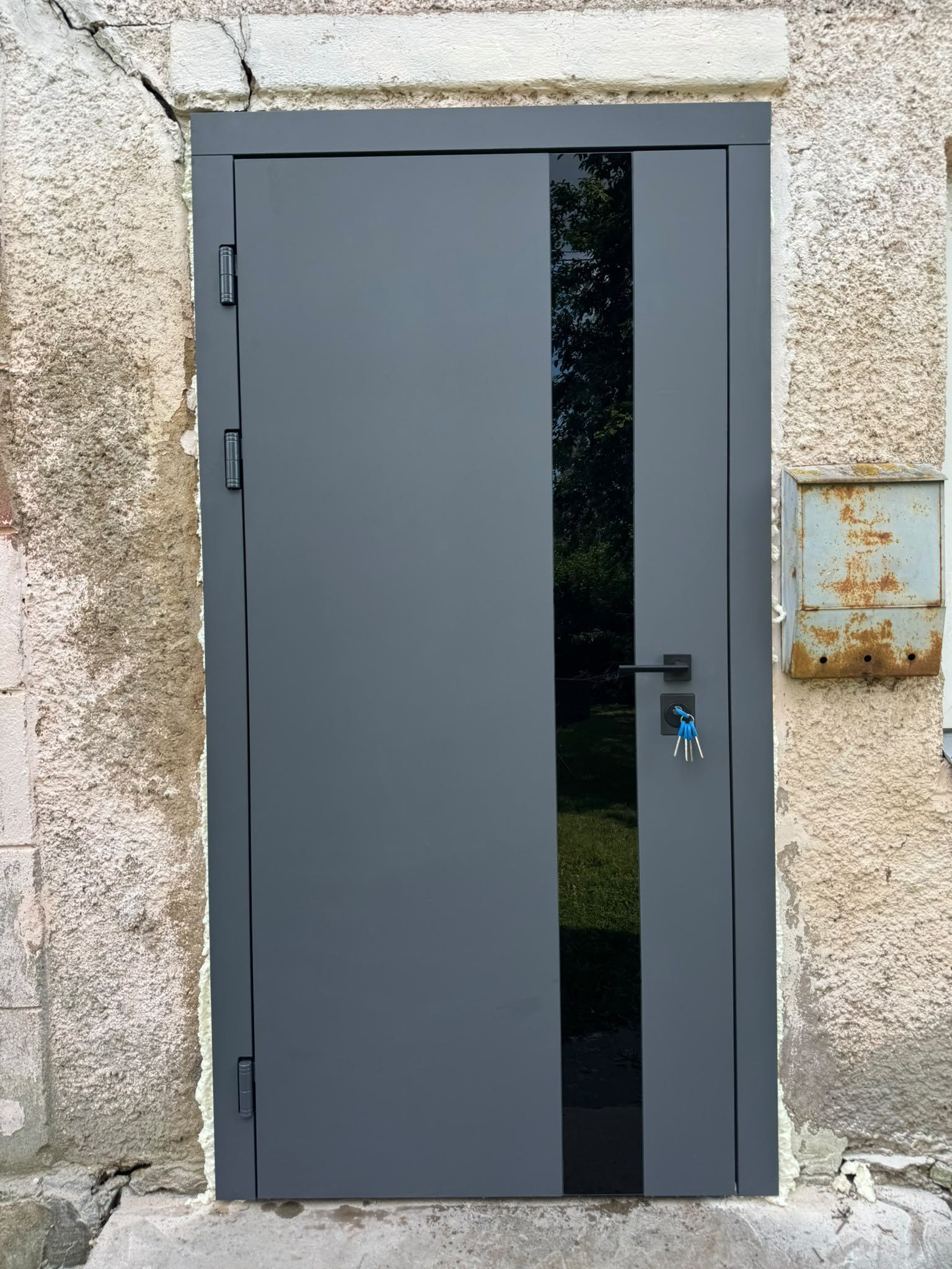Privātmājas durvis ar antracīta toni un baltu ābeles apdari, nodrošinot drošību un siltumizolāciju